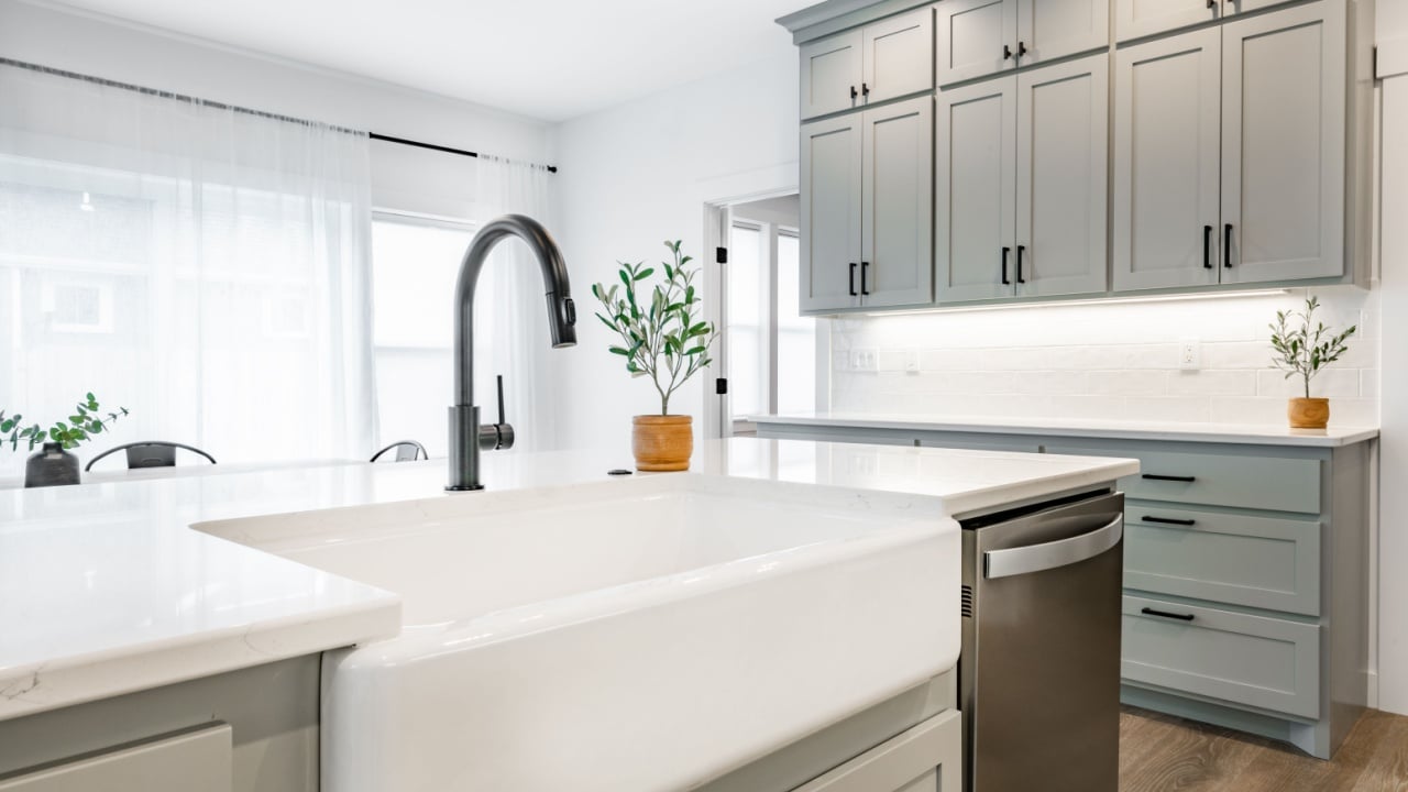modern farmhouse style kitchen with stainless appliances white counter top raw wood dining table kitchen island and mirror reflection