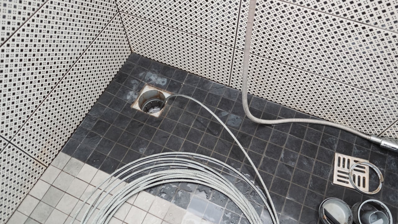 Sewer cleaning. Cleaning the sewer with a cable. Plumber using a drain snake to unclog the shower. Plumbers extracting snake tool.